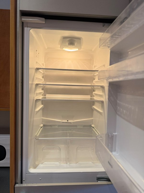 Open empty refrigerator with shelves and interior light on