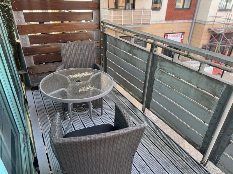 Outdoor balcony with glass-top table, wicker chairs and city views