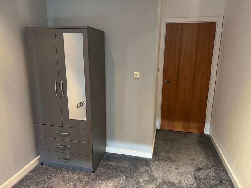 Bedroom corner with grey wardrobe, wooden door, and carpeted floor