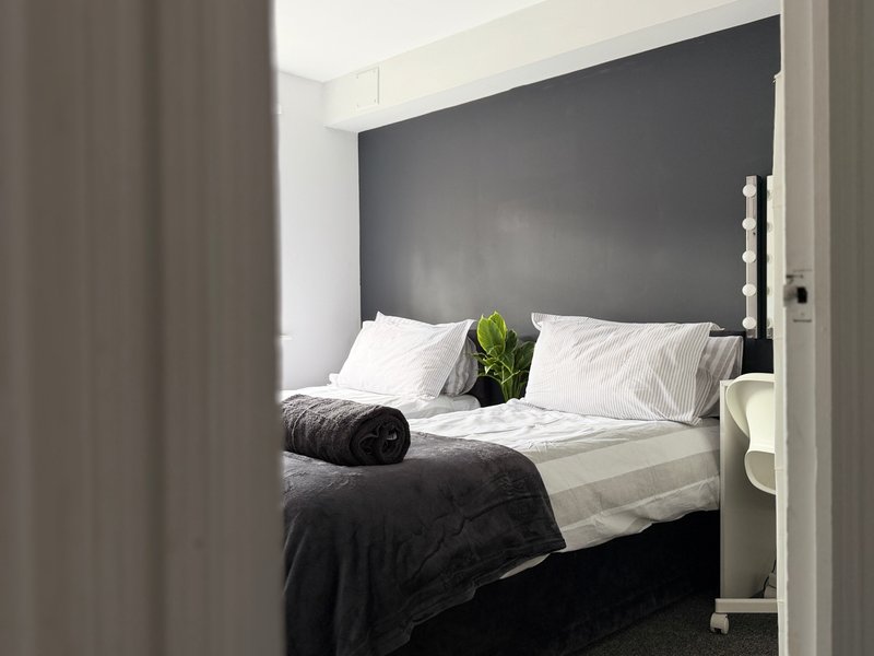 Modern bedroom with dark grey headboard, white pillows, black and white bedding, potted plant
