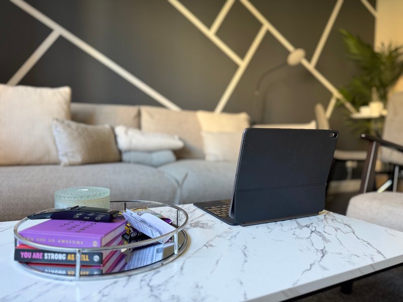 Modern living room with geometric wall art, gray sofa, marble coffee table with tablet and books