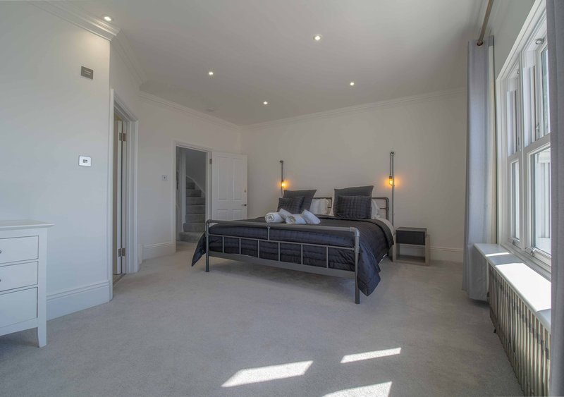 Spacious modern bedroom with double bed, bedside lamps, white furniture and large windows