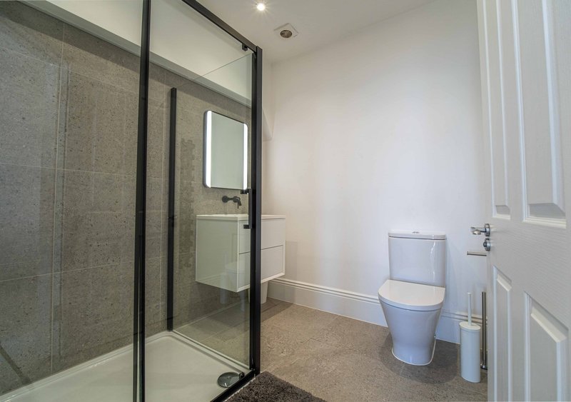 Modern bathroom with walk-in shower, toilet, sink and tiled flooring