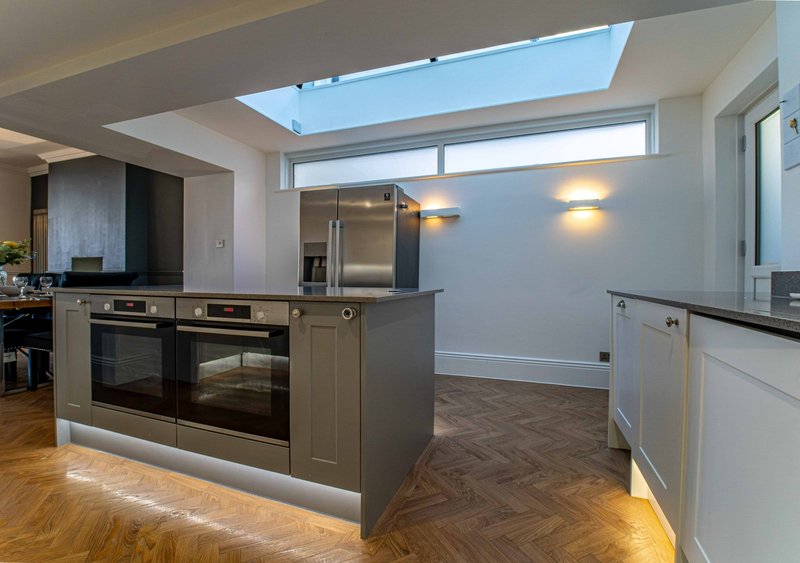 Modern kitchen with island, stainless steel appliances, skylight and wooden flooring