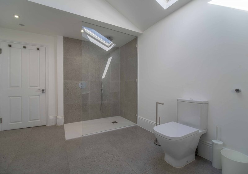 Modern bathroom with walk-in shower, toilet, and skylight in contemporary grey and white design