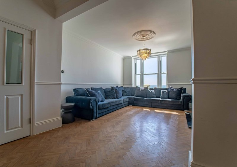 Spacious living room with blue corner sofa, wooden herringbone floor, and pendant light