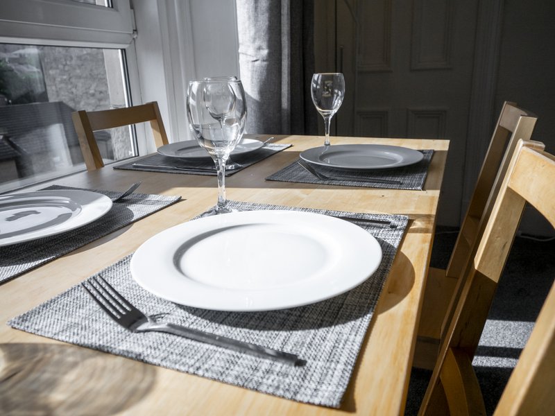 Formal dining table set with place settings, glasses, and wooden chairs