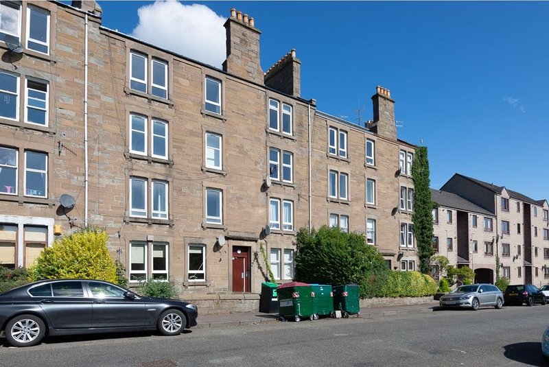 Stone terraced residential building with parked cars and street view