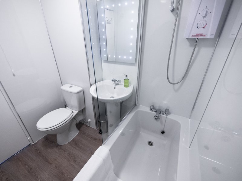 Modern bathroom with toilet, bathtub, shower enclosure and pedestal sink