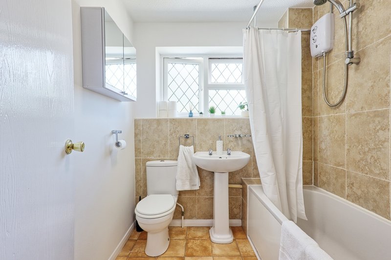 Bathroom with pedestal sink, toilet, bathtub, shower curtain and tiled walls