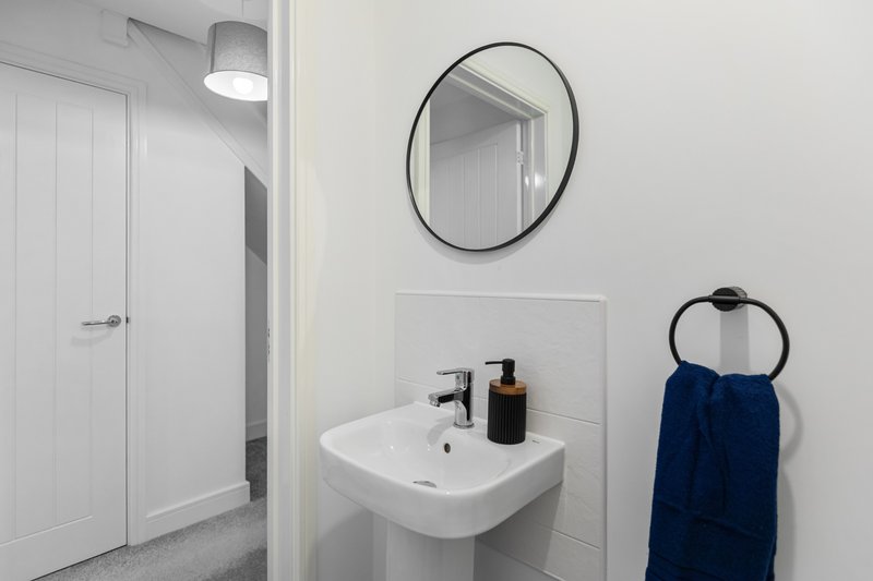 Modern bathroom with white sink, round mirror, blue towel and pendant lighting