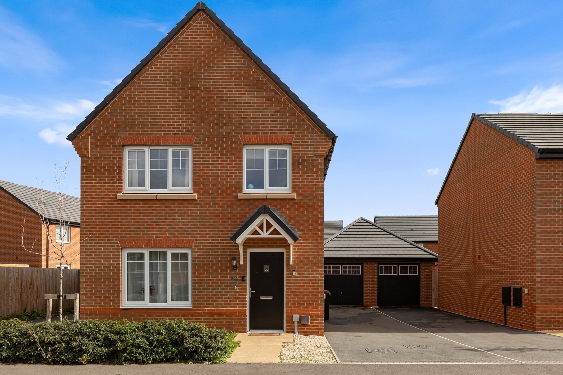 Modern brick detached house with driveway, garage, and front garden