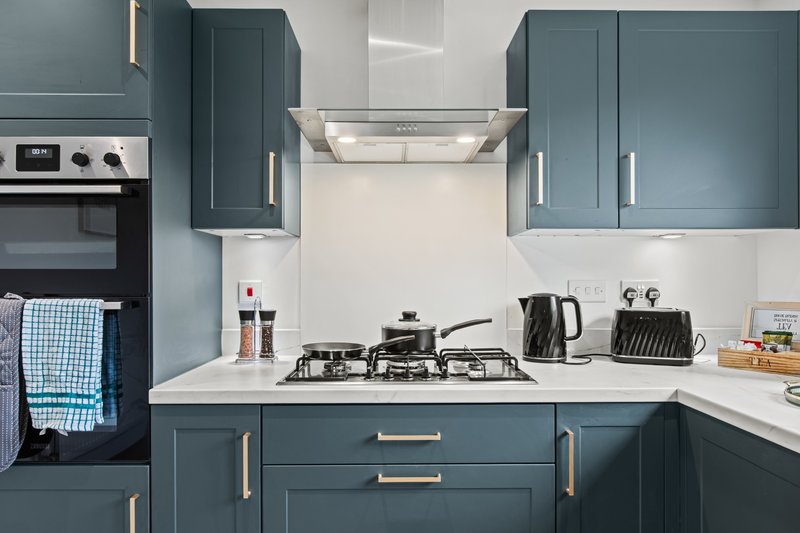 Modern kitchen with teal cabinetry, white countertops, gas cooktop and integrated appliances