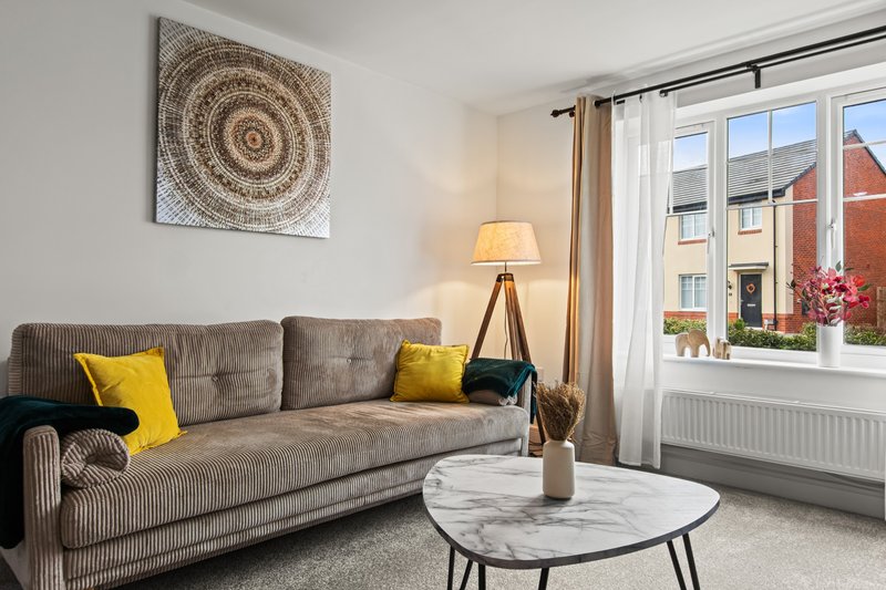 Bright living room with gray sofa, yellow cushions, marble coffee table and large windows