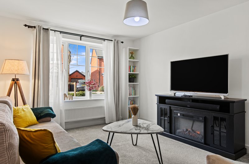 Bright living room with fireplace TV unit, sofa, coffee table and window view