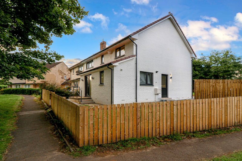 White brick semi-detached house with wooden fence, driveway and front garden