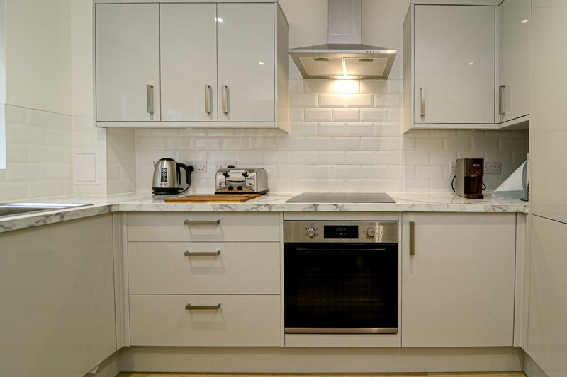 Modern kitchen with cream cabinetry, white subway tile splashback, integrated oven and hob