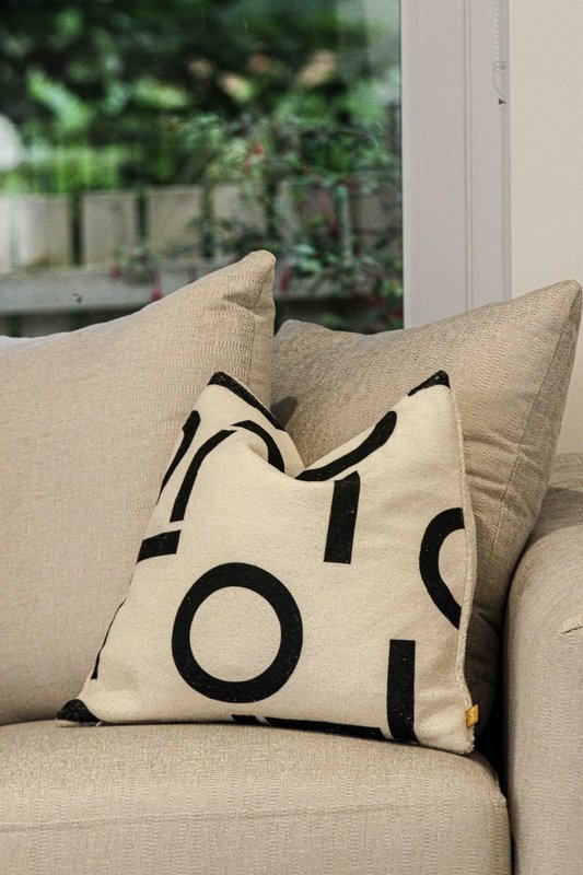 Beige sofa with geometric patterned cushion, garden view through window