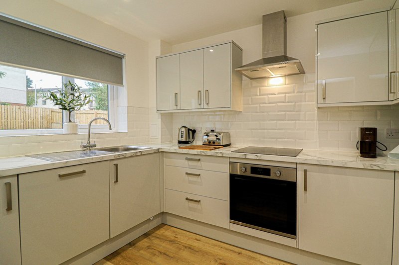 Modern kitchen with cream cabinets, stainless steel appliances, white subway tile backsplash and wooden flooring