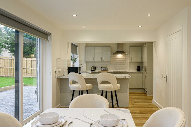 Open-plan kitchen and dining area with cream cabinetry, wooden flooring, and garden view