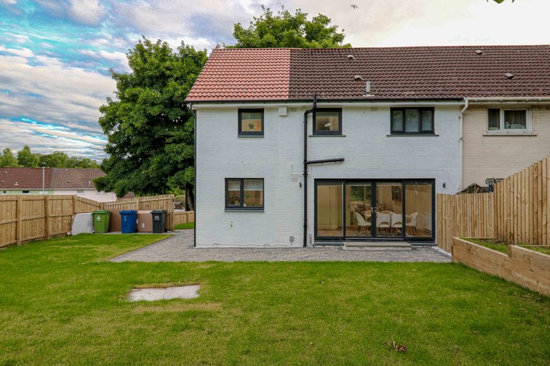 Modern white brick house with garden, large patio doors and wooden fence surrounding