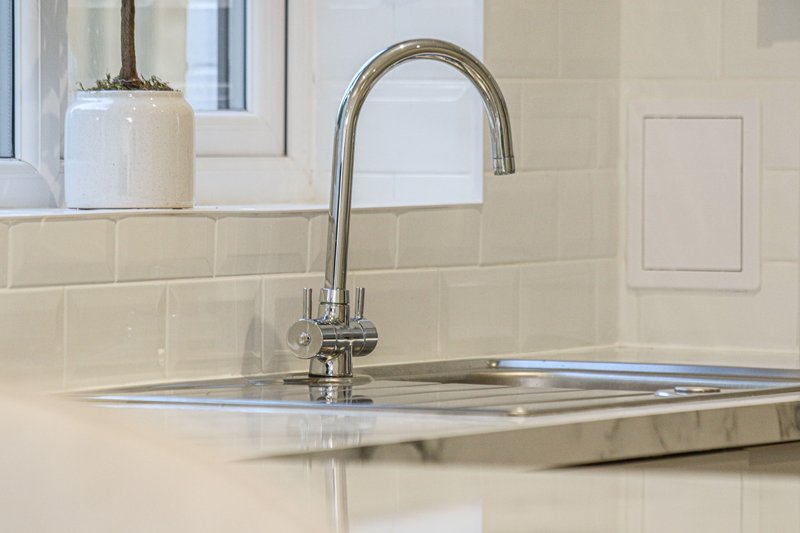 Modern kitchen sink with chrome faucet, white subway tile backsplash and pendant light