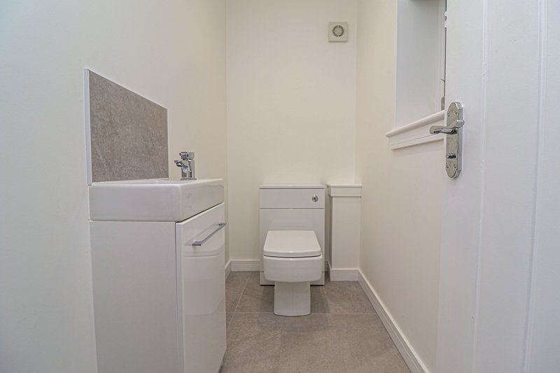 Compact bathroom with white sink vanity, toilet, and grey tiled flooring