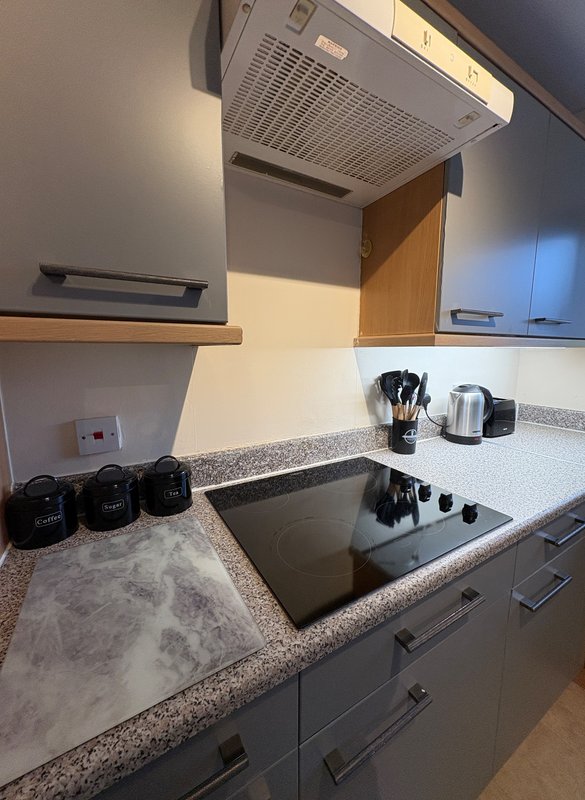 Modern kitchen with granite countertop, stainless steel sink, range hood, and storage containers