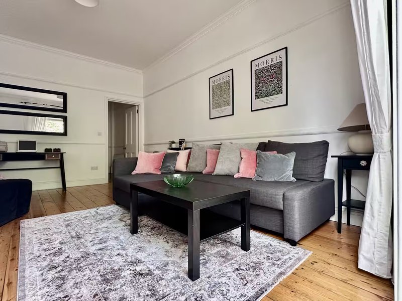 Modern living room with grey corner sofa, black coffee table, wooden flooring and wall art
