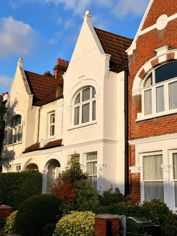 Cream and brick terraced houses with bay windows, manicured front garden, clear blue sky
