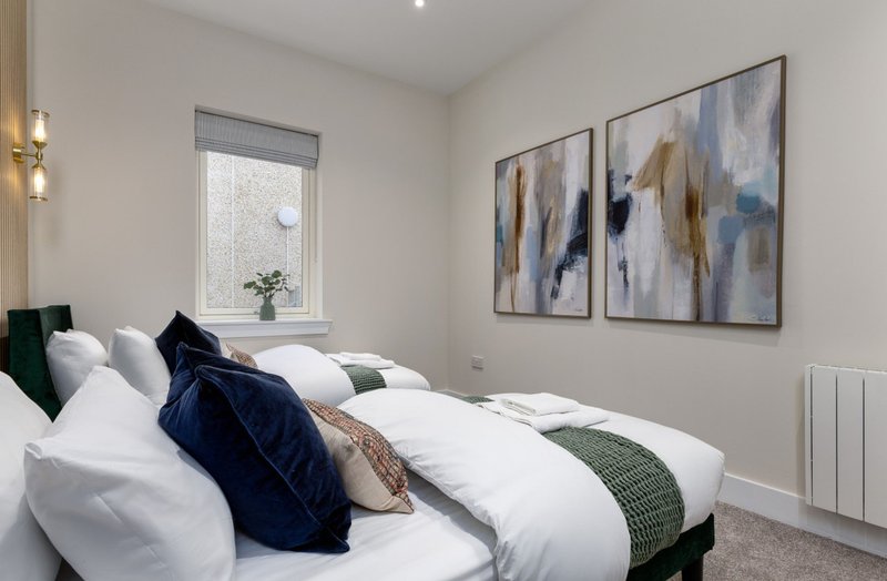 Modern bedroom with twin beds, white bedding, decorative pillows and abstract wall art