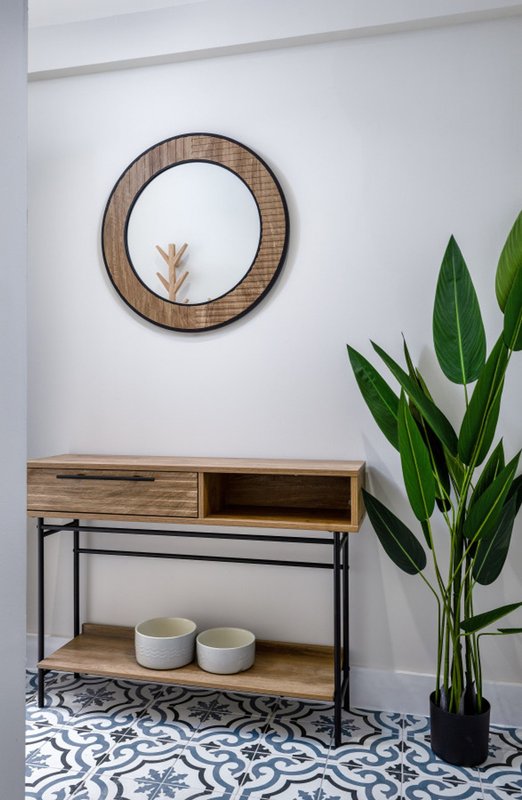 Entryway with wooden console table, round mirror, potted plant and patterned floor