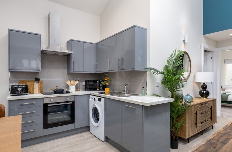 Modern kitchen with gray cabinetry, white countertops, integrated appliances and island unit