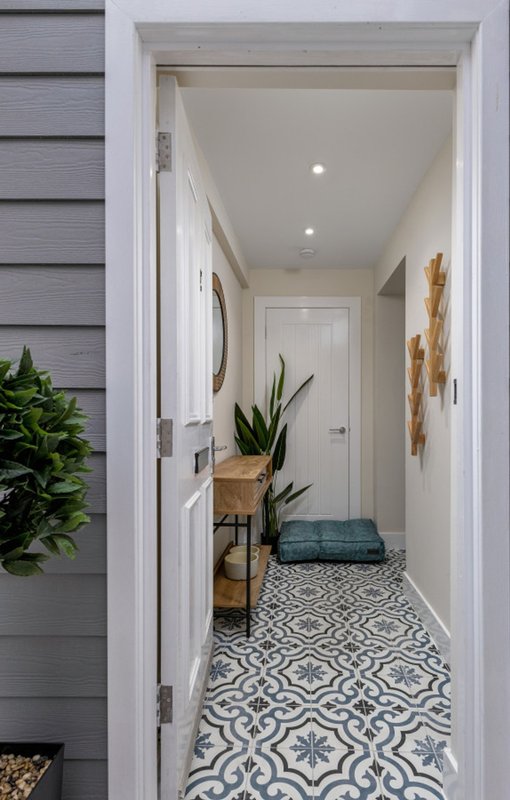 Bright hallway with patterned tile floor, potted plants, and recessed ceiling lights
