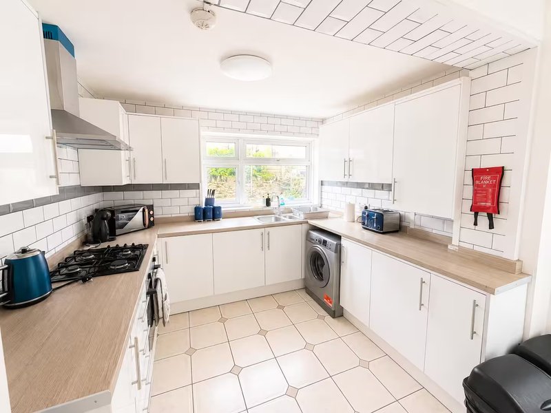 Modern kitchen with white cabinetry, wood countertops, subway tile splashback and integrated appliances