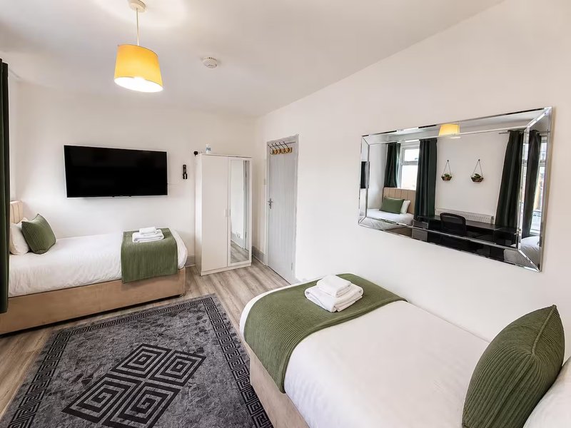 Modern bedroom with two single beds, TV wall-mount, large mirror, pendant lamp and neutral decor