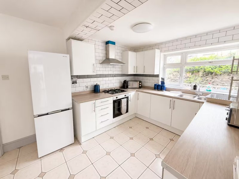 Modern kitchen with white cabinetry, white subway tile backsplash, tiled flooring and garden view