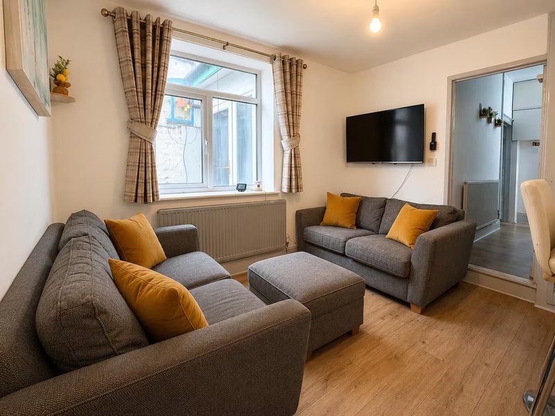 Modern living room with two gray sofas, yellow cushions, wooden floor and wall-mounted TV