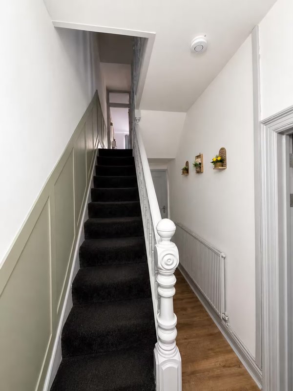 Staircase with black carpet, white bannister and painted walls leading upward
