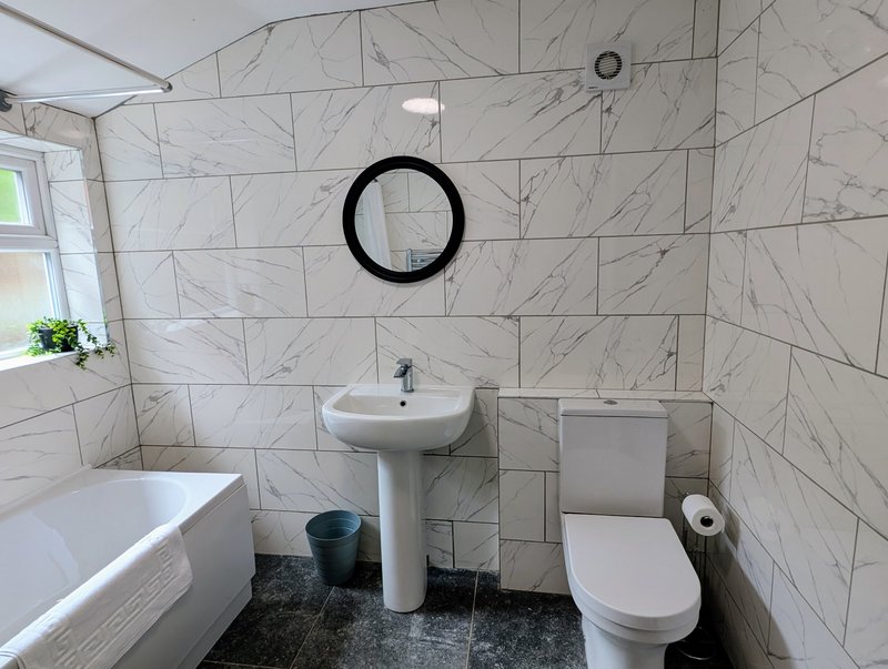 A clean, modern bathroom with a shower over the bath, practical for contractors getting ready for an early start or unwinding after work. Complimentary toiletries are provided for added convenience