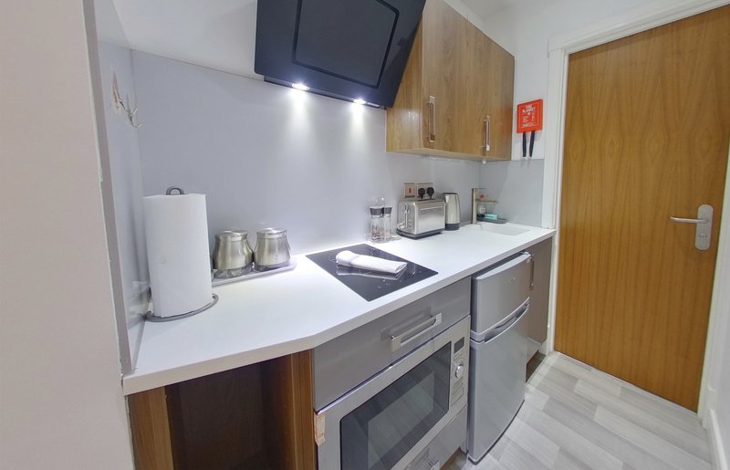 Modern kitchen with built-in oven, hob, white countertop and wall-mounted TV