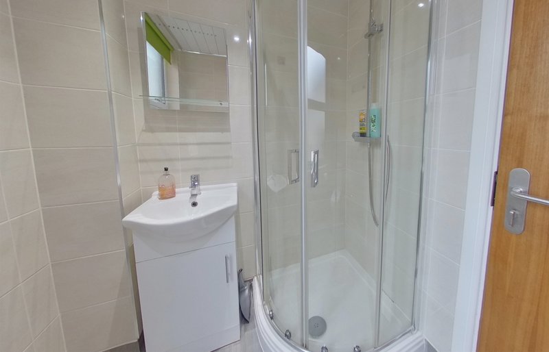 Modern bathroom with white sink vanity, mirror, and glass shower enclosure