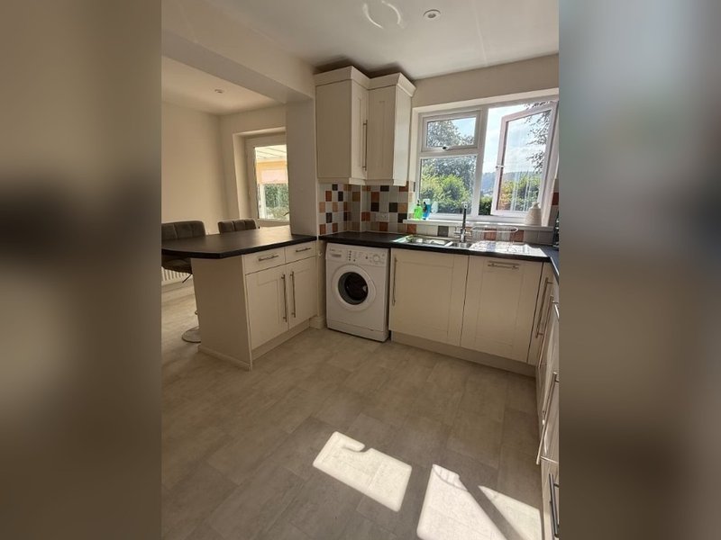 Modern kitchen with cream cabinets, black worktops, integrated washing machine and tiled backsplash