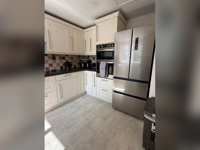 Modern kitchen with white cabinetry, stainless steel appliances, tiled backsplash and grey flooring