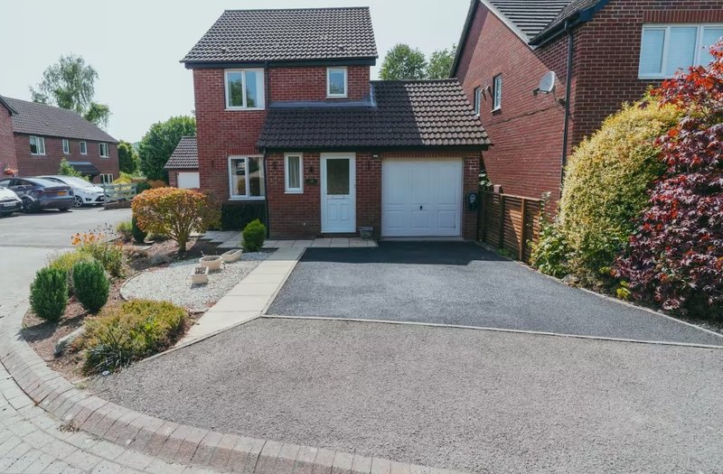 Red brick detached house with driveway, garage, front garden and landscaping
