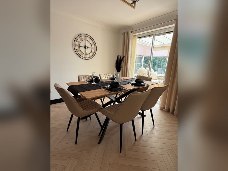 Modern dining room with black table, tan chairs, round wall clock and large windows