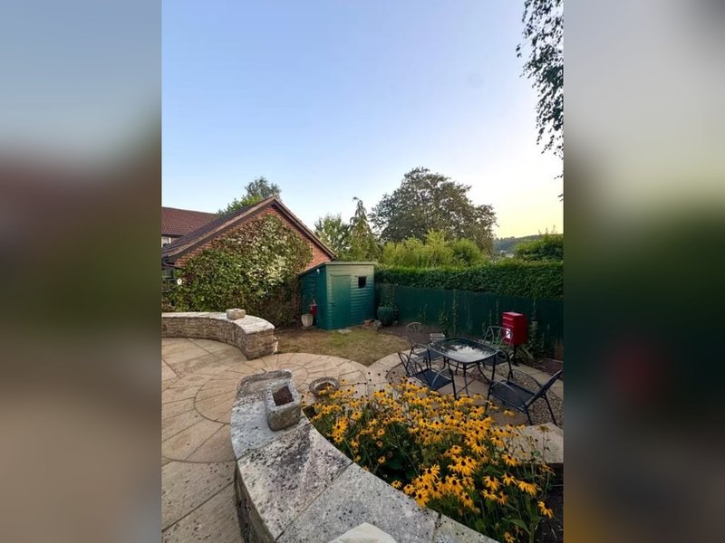 Garden patio area with stone seating, flower beds, shed and outdoor furniture