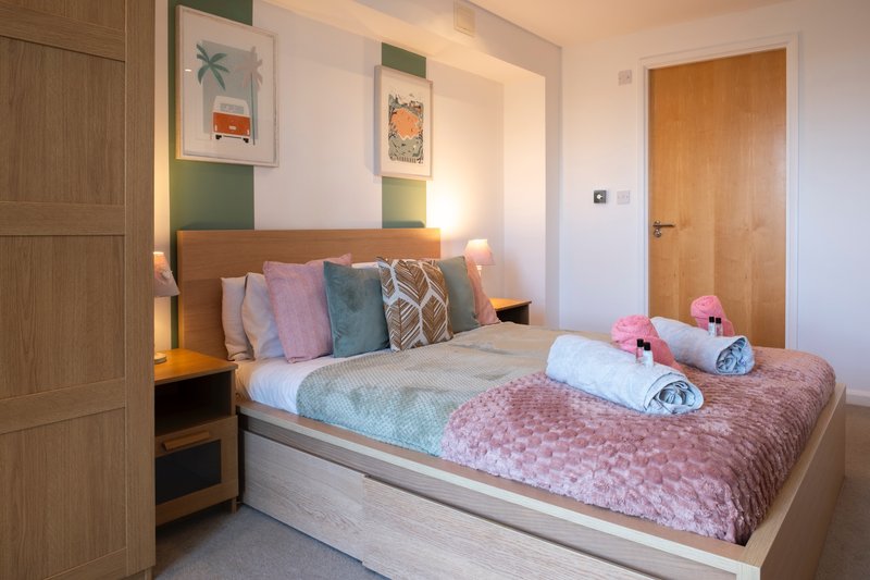 Modern bedroom with double bed, colorful pillows, bedside lamps and wooden doors