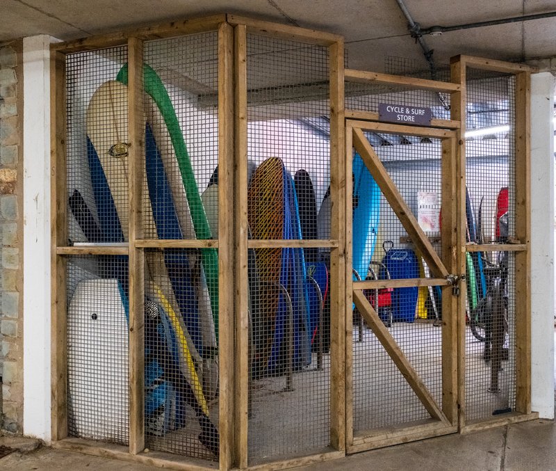 Storage cage with wooden frame containing surfboards and water sports equipment