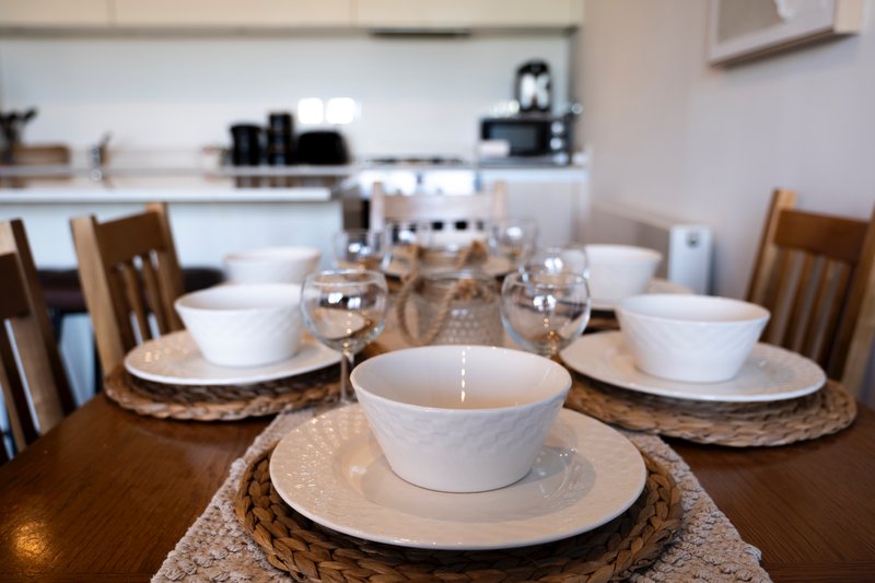 Dining table set for multiple guests with white bowls, plates, and glassware